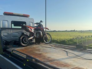 offroad motorbike on back of a flatbed with field in the background