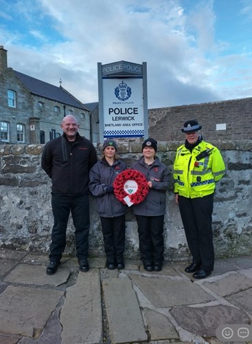 Police Scotland Youth Volunteer holding poppy wreath in Shetland beside the Scottish Fire and Rescue Service