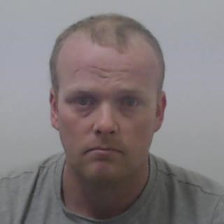 Image of jailed man Richard Pettigrew - 30 year old man with receding fair hair, frowning expression wearing grey tshirt.