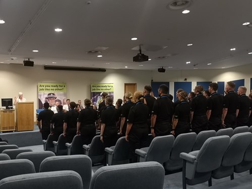 Police Scotland probationary constables dressed in black uniforms raise their right hands to take the Oath of Office in the Jackton Lecture Theatre.