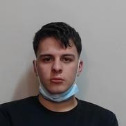 Image of convicted man Kevin Richardson - man in 20s with medium length dark hair, wearing black tshirt and blue and white facemask round his chin