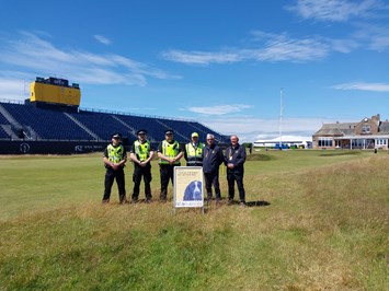 image of Project Servator officers with representatives from the R&A and Security Scotland, standing in front of the grandstand and clubhouse at Royal Troon Golf Club