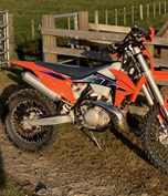 Orange off-road motorbike next to fence