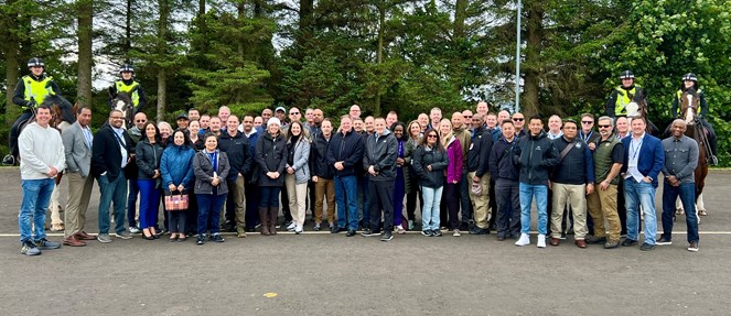 Around 50 delegates from the FBI National Executive Institute course posing with four Police Scotland Mounted Branch officers on horseback.
