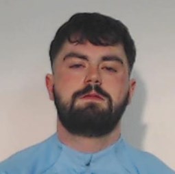 24-year-old man with dark hair and beard wearing blue top