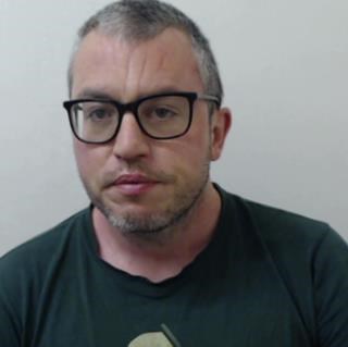 Image of convicted man Martin Ready - man with short grey hair and beard wearing dark-framed glasses and black tshirt