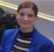 32-year-old white woman with brown hair wearing black and white top and blue jacket