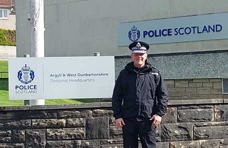 Police officers stood outside a building in front of a sign at Police Scotland HQ in West Dunbartonshire