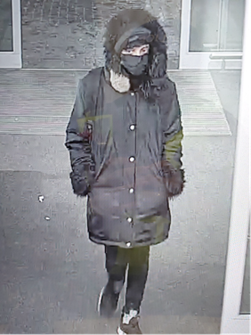 CCTV image of missing person Santra Sanju wearing long black coat with the hood up, black mask, and black trousers